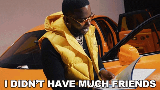 a man in a yellow vest is standing in front of an orange car with the words i did n't have much friends