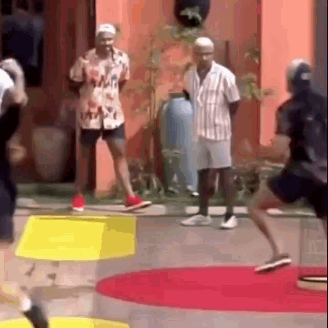 a group of men are standing on a red carpet in front of a house .