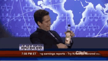 a man holding a bottle in front of a world wide news sign