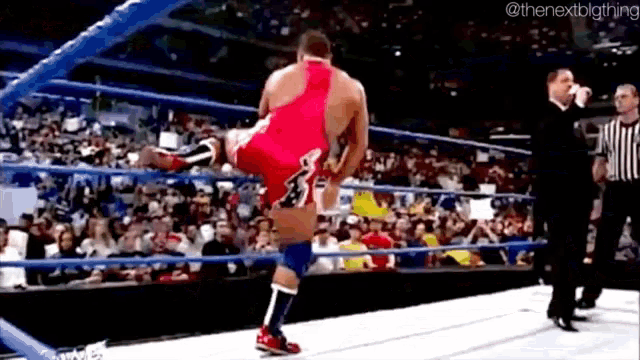 a wrestling match is being held in a ring with a referee watching .
