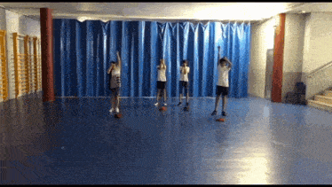 a group of people are standing in a room with blue curtains