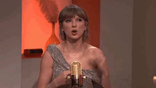 a woman in a silver dress is singing into a gold microphone