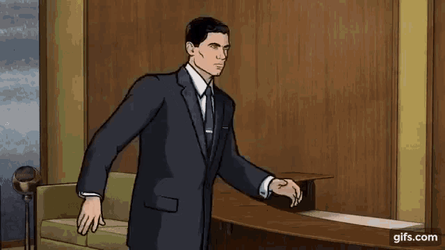a man in a suit and tie is standing next to a couch in a room .
