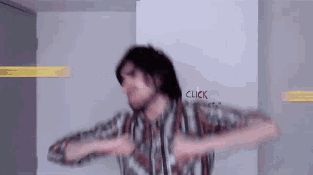 a man in a striped shirt is dancing in front of a sign that says click