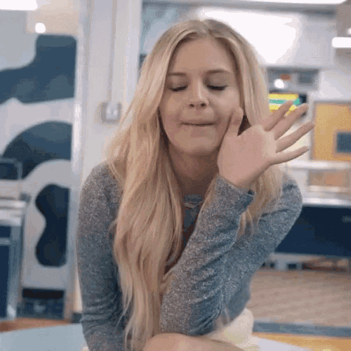 a woman with blonde hair is making a funny face with her hand on her face