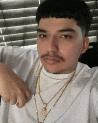 a man with a mustache wearing a white shirt and gold chains