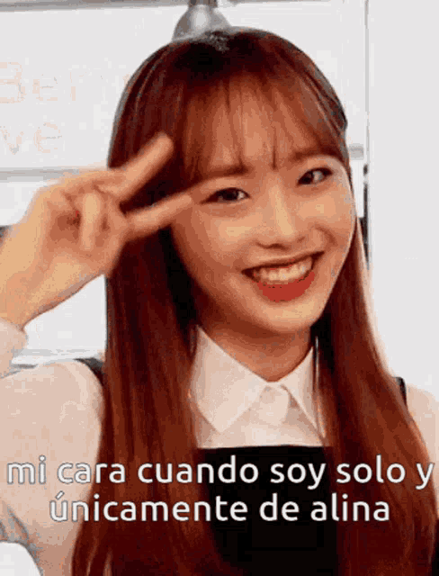 a girl is smiling and making a peace sign with her hands