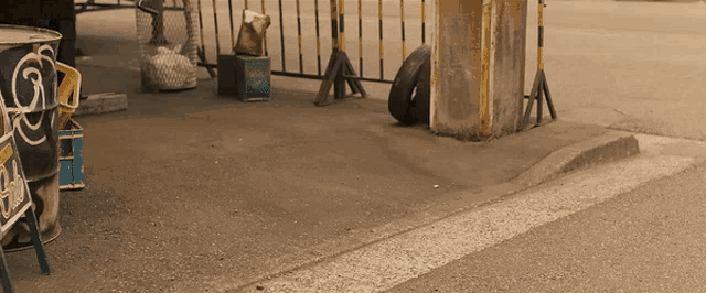 a tire is sitting on the side of the road next to a barrel that says ' coca cola ' on it