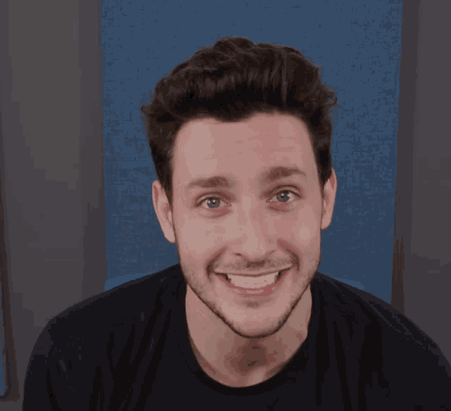 a man with a beard and a black shirt smiles
