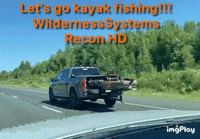 a truck is driving down a highway with a kayak in the bed