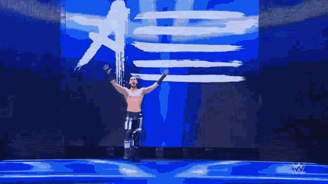 a wrestler named mustafa ali stands in front of a flag