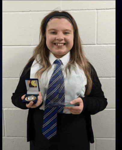 a girl wearing a blue tie is holding a trophy