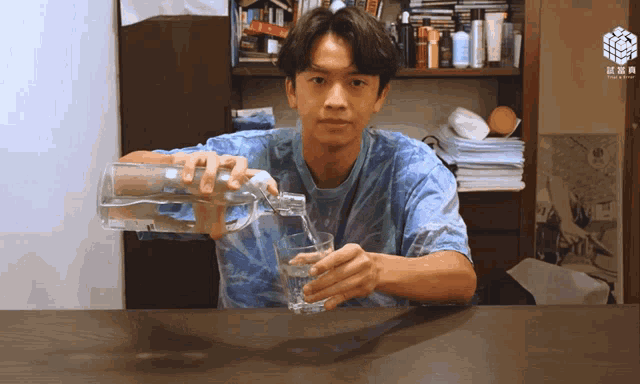 a man pouring water from a pitcher into a glass on a desk