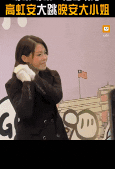 a woman in a suit is standing in front of a wall with chinese characters