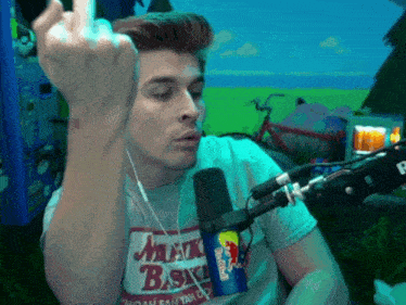 a man wearing a shirt that says milk basket is giving the middle finger in front of a microphone