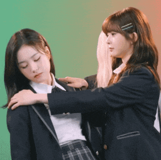 two girls in school uniforms are standing next to each other and one is putting her hand on the other 's shoulder