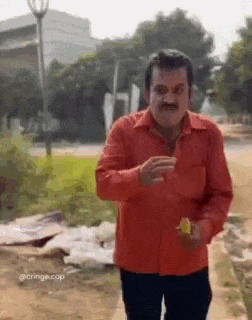 a man in a red shirt is walking down a dirt road while holding a banana .