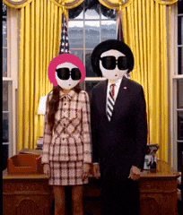 a man and a woman standing next to each other in front of a window
