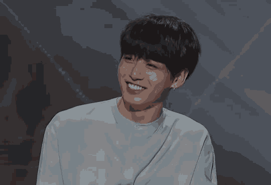 a young man wearing a blue shirt and ear buds smiles