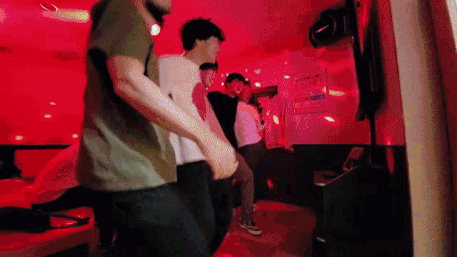a group of people are dancing in a room with red lighting