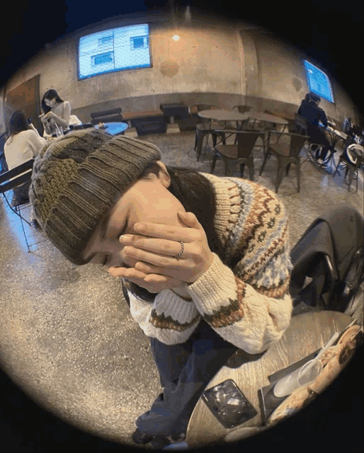 a woman wearing a sweater and a beanie covering her face