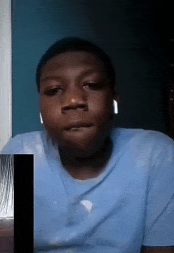 a young man wearing headphones is making a funny face while sitting in front of a window .