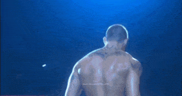 a man with a tattoo on his back stands in a ring