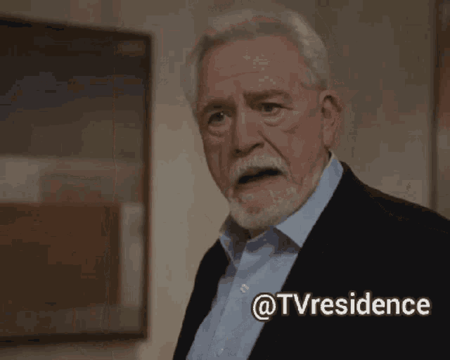 a man in a suit and blue shirt is standing in front of a painting with the words @tvresidence below him