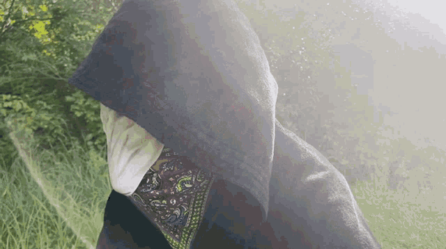 a person wearing a hooded jacket and a bandana around their face