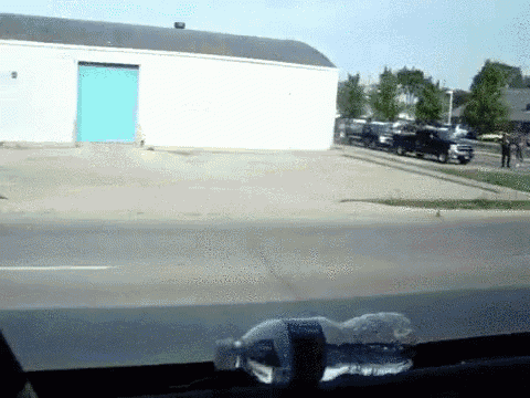 a bottle of water sits on the windshield of a car in front of a building