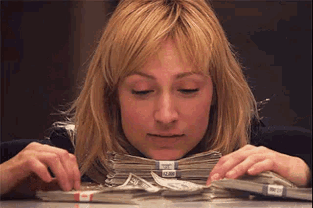 a woman is sitting at a table with stacks of money on it