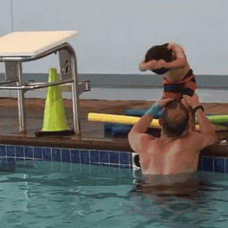 a man holds a child on his shoulders in a pool