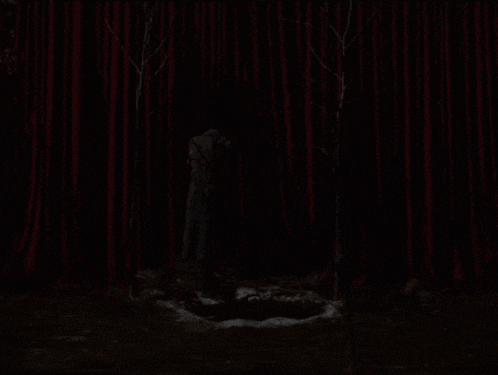 a man in a dark room with a red curtain