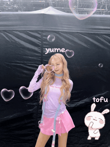 a girl blowing soap bubbles in front of a black tent that says yume on it