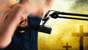 a man wearing a cowboy hat is singing into a microphone in front of a cross