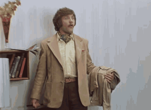 a man standing in front of a bookshelf holding a coat