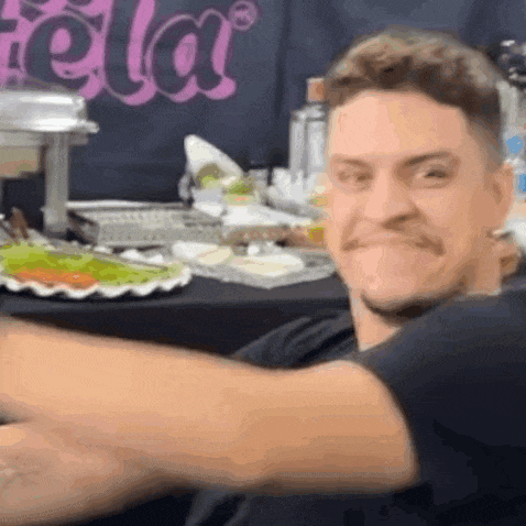 a man with a mustache is sitting at a table with a plate of food on it .