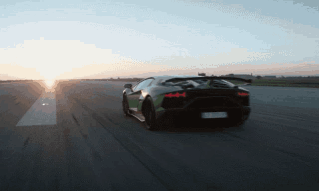 a black and green lamborghini is driving down a runway