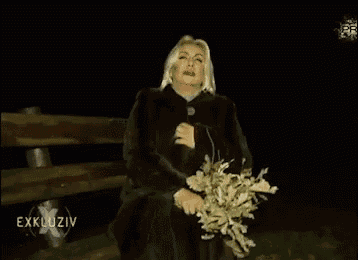 a woman in a fur coat holds a bouquet of flowers