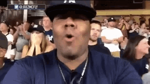 a man wearing a ny hat is blowing a kiss in front of a crowd of people