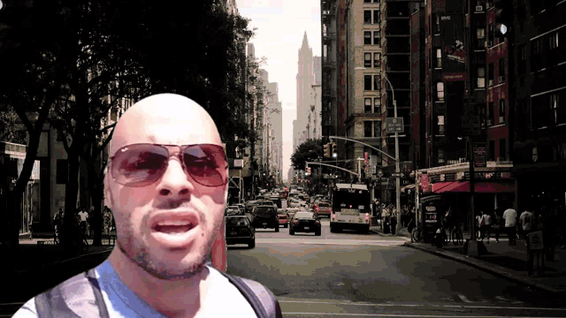 a man wearing sunglasses stands in front of a busy street