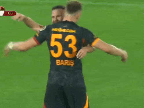 a soccer player with the number 53 on his back is hugged by another player
