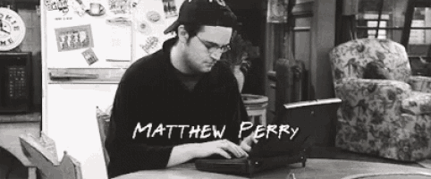 matthew perry is sitting at a table using a laptop computer