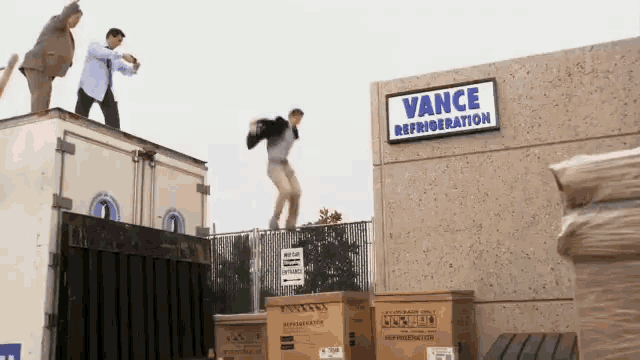 two men standing on top of a vance refrigeration container