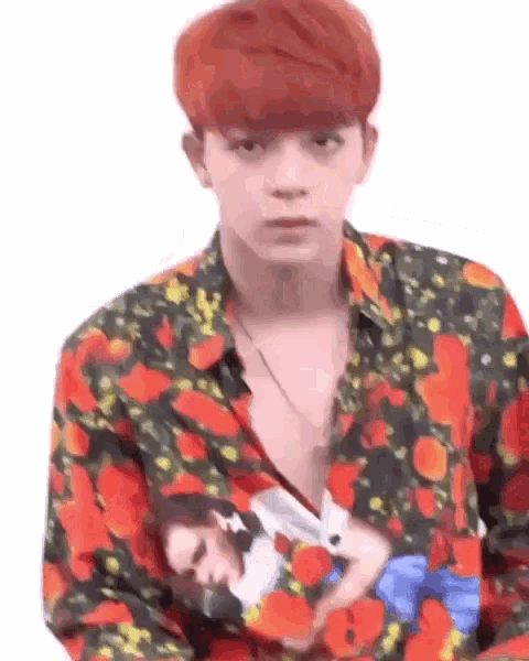 a young man with red hair is wearing a floral shirt with a picture of a woman on it .