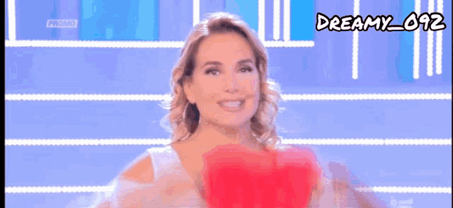 a woman is holding a red heart in front of her face and the words tanto cuore are below her