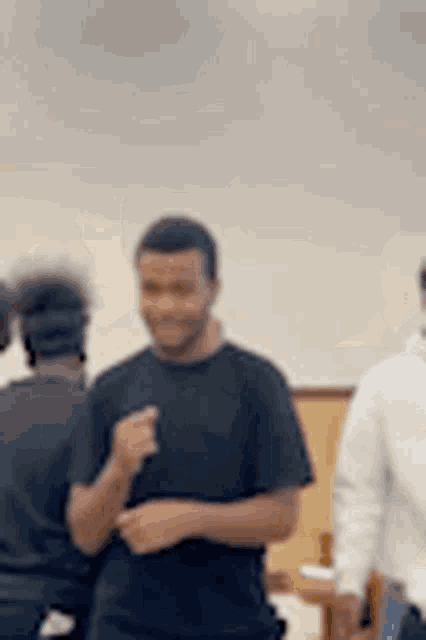 a man in a black shirt is talking to another man in a room .