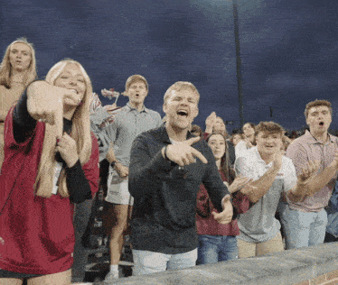 a group of people are watching a football game and one of them is wearing a shirt that says ' georgia tech ' on it