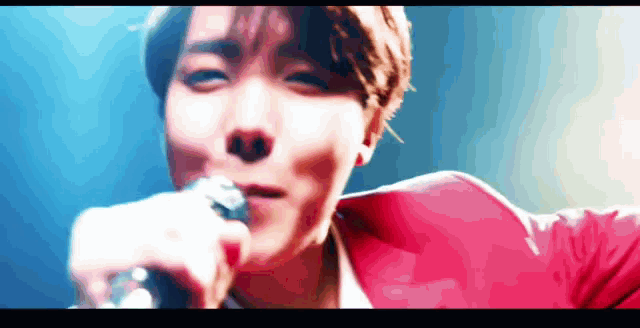 a man in a red jacket is singing into a microphone on a stage .