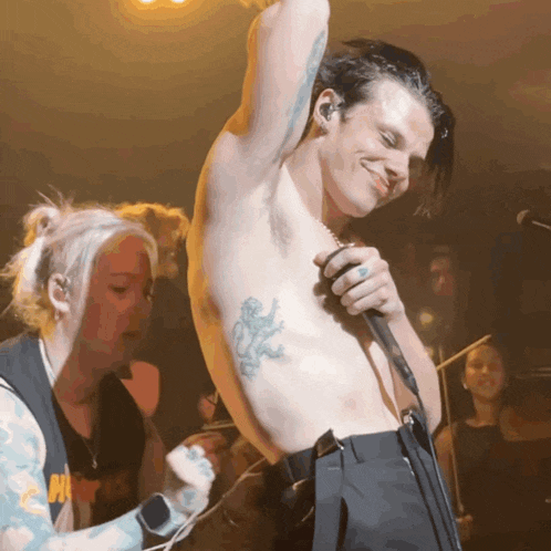 a man without a shirt is singing into a microphone with a tattoo of a lion on his stomach